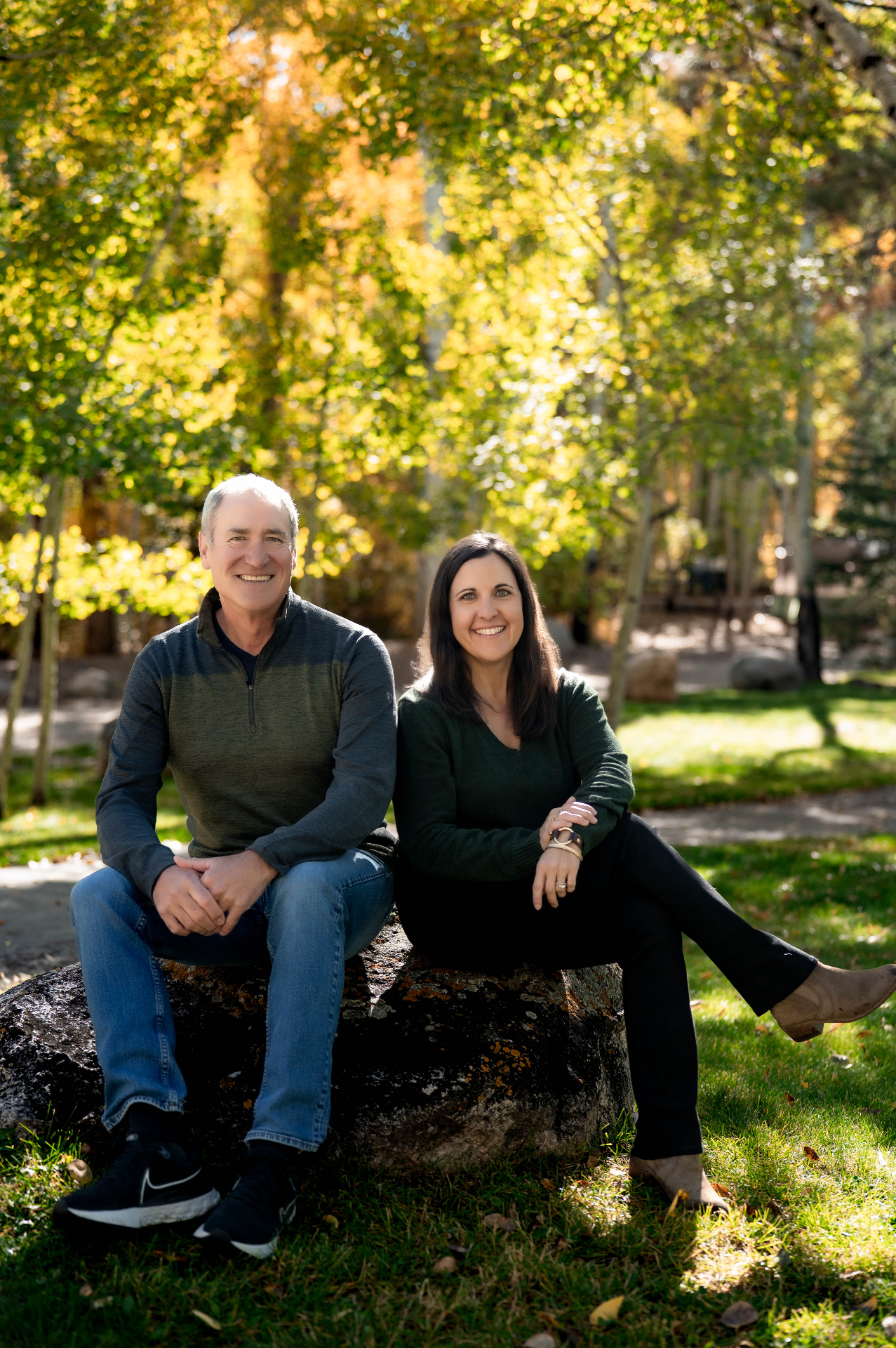 Shawn and Jillian sitting on a rock beneath golden aspen trees
