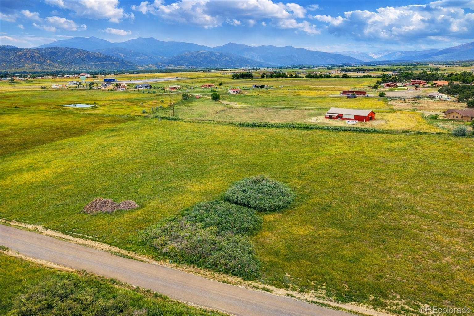 Open Colorado ranch land with a red barn and mountains in the distance